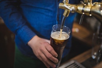 A bartender pouring beer, symbolizing the importance of finding qualified bar staff through a bar staffing agency.